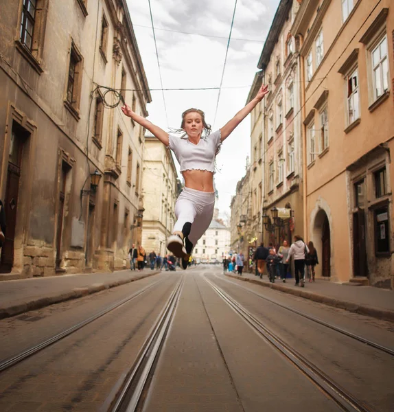 Gymnastka sportovní dívka skákání na ulici starého města v létě — Stock fotografie