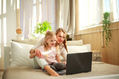 Mutlu aile anne ile kızı evde bilgisayar dizüstü kullanarak