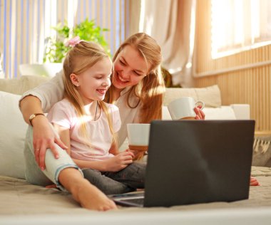 Mutlu aile anne ile kızı evde bilgisayar dizüstü kullanarak