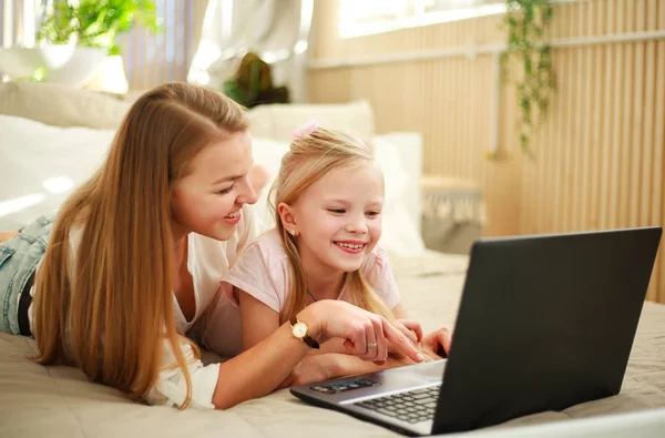 Happy family mother with daughter using computer laptop at home