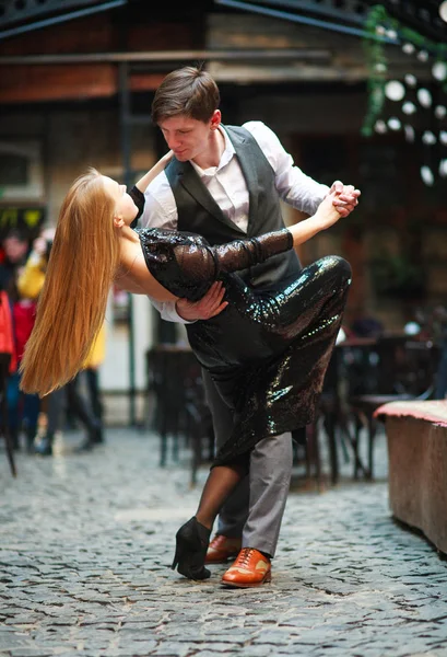 Радостная молодая пара в любви танцует латынь на вечерней улице — стоковое фото