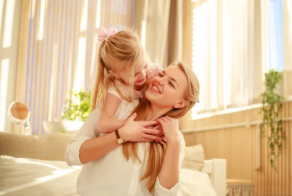 Moeder en dochter vreugdevol knuffelen thuis op bed — Stockfoto