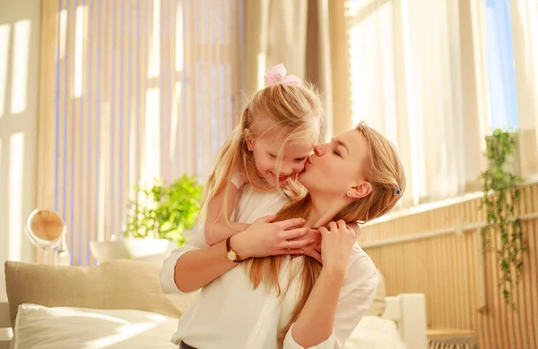 Moeder en dochter vreugdevol knuffelen thuis op bed — Stockfoto