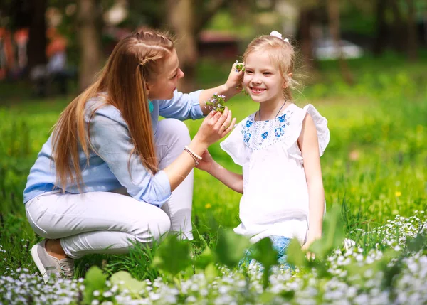 Mãe com filha em verde florescendo parque de verão no prado — Fotografia de Stock