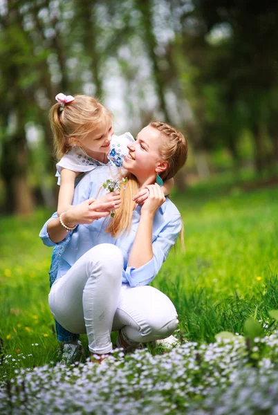 Mãe com filha em verde florescendo parque de verão no prado — Fotografia de Stock