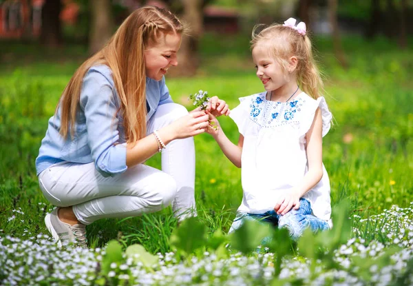 Mãe com filha em verde florescendo parque de verão no prado — Fotografia de Stock