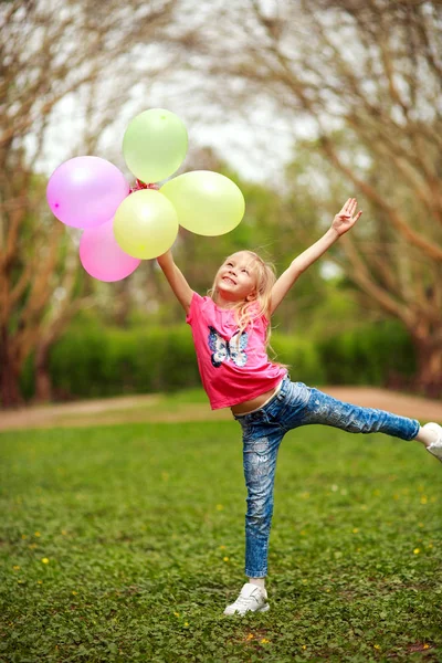 Ragazza felice con palloncini che salta nel parco cittadino festeggiando l'estate — Foto Stock