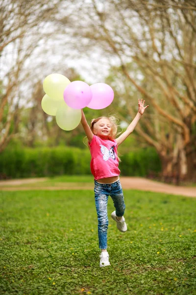 Chica feliz con globos saltando en el parque de la ciudad celebrando el verano — Foto de Stock