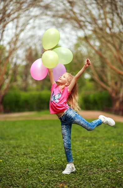Menina feliz com balões pulando no parque da cidade comemorando o verão — Fotografia de Stock