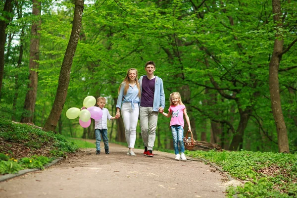 Padre de familia y madre con dos hijos caminando en el parque de verano — Foto de Stock