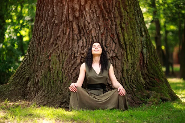 Chica en vestido se sienta disfrutando de la naturaleza medita, practica yoga —  Fotos de Stock