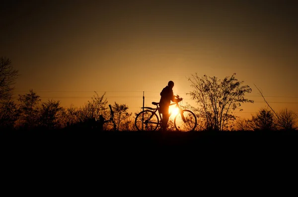 Silhueta de um menino com bicicleta no fundo do pôr do sol brilhante — Fotografia de Stock