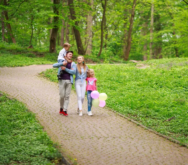Feliz familia joven con sus dos hijos están caminando en verano — Foto de Stock