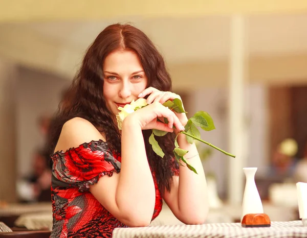 Chica en vestido sentado en la mesa en el restaurante y disfrutar del aroma —  Fotos de Stock