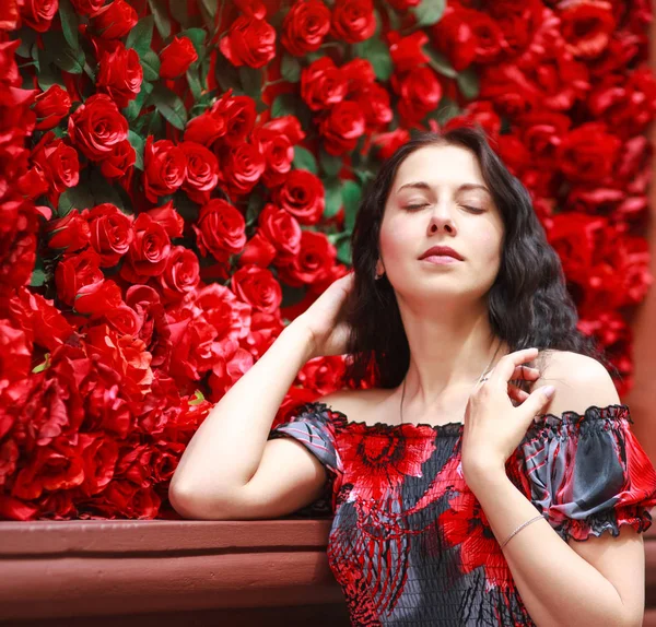 Retrato de mulher sonhadora elegante no vestido em rosas vermelhas — Fotografia de Stock