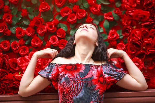 Portrét elegantní ponuré ženy v šatech na rudých růžích — Stock fotografie