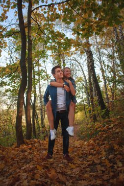 Mutlu genç çift sonbahar orman parkında yürürken eğleniyor.