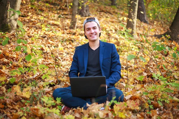 Молодий хлопець бізнесмен в класичній синій куртці з ноутбуком сидить — стокове фото