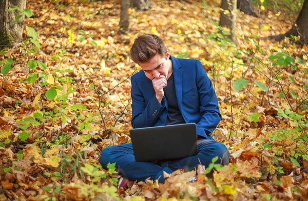 Joven hombre de negocios en chaqueta azul clásico con portátil sentado —  Fotos de Stock