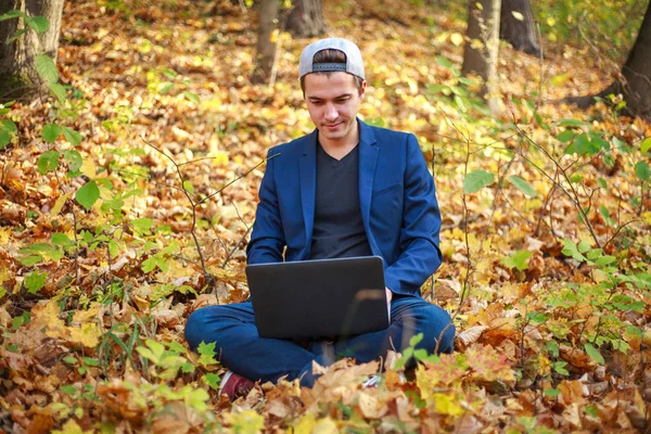 Молодий хлопець бізнесмен в класичній синій куртці з ноутбуком сидить — стокове фото