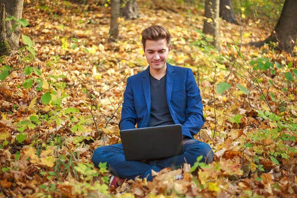 Mladý muž podnikatel v klasické modré bundě s notebookem sezení — Stock fotografie
