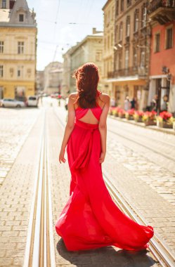 Tutkulu genç bir kız, Ukrayna 'nın eski bir Avrupa şehrinin caddesinde uzun kırmızı elbiseli bir bayan.