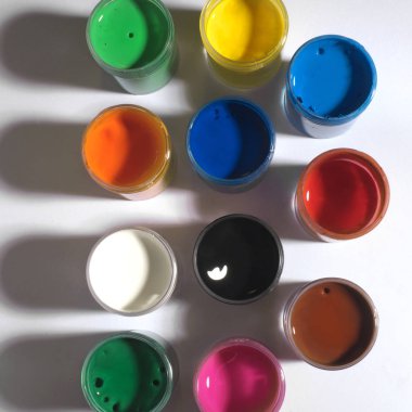 Beyaz bir arka plan üzerinde küçük kavanozlara gökkuşağının boya renkleri 