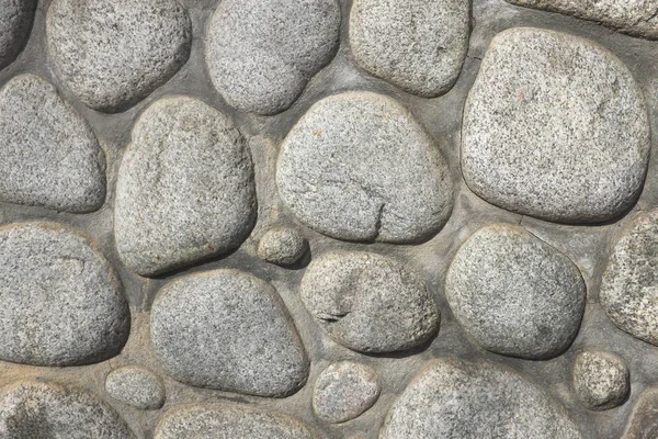 Round stones from the river, arranged and connected with cement mortar, background and texture ...