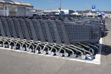 Bir otopark arka planda bir hipermarket mağazasının önünde plastik alışveriş arabaları satırları ...  