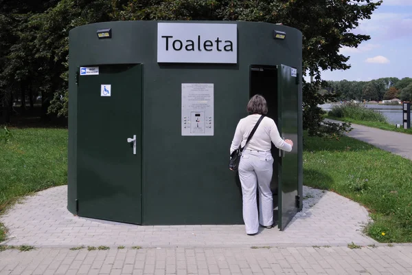 Automatic toilet, public facility in the park, woman enters the previously paid toilet, entrance for disabled on the left ...