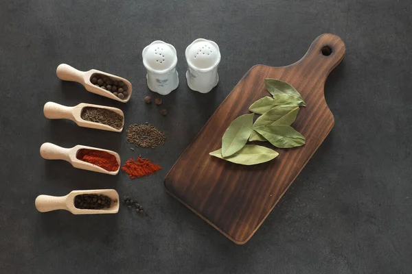 stock image Herbs, spices for dishes and kitchen board on a dark table ...