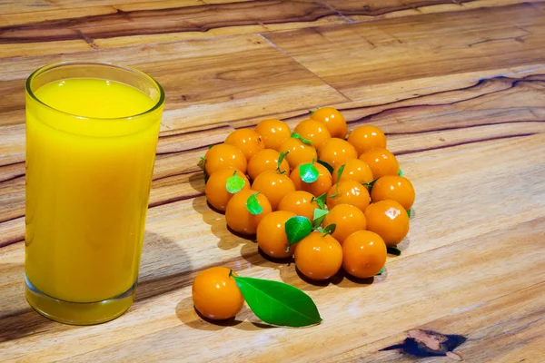 Orange juice and deletable imitation fruits on table wooden. loo — Stock Photo, Image