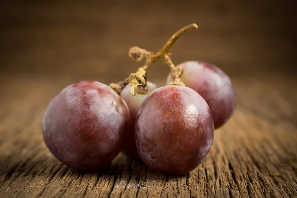 Uvas rojas sobre mesa de madera — Foto de Stock