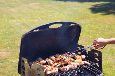 Kadın tavuk eti ızgara ve barbekü maşa kullanarak. Kavram gıda