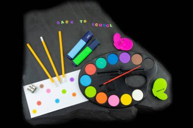 Kopya alanı üzerinde tahta arka plan ile portre renkli okul malzemeleri. Geri okula renkli harflerle yazı tahtası üzerinde yazılı. Kavram eğitim