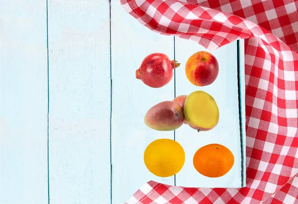 Food recipe template. Ripe fruits (pomegrate, apple, mango, orange, grapefruit) on bright wooden table. Health care, diet and nutrition concept.