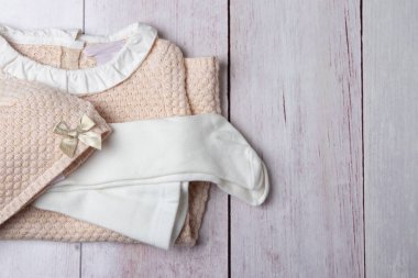 Üstten görünüm parlak bir rustik ahşap masa üzerinde kız için renkli elbise yığını üzerinde. Alan, ürün görüntü montaj. Konsept reklam ve çocuk moda alışveriş.
