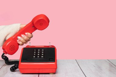 İletişim arka plan. Vintage eski kırmızı telefon ahizesi ve yakışıklı pembe arka planda tutan iş kadının el ile iletişim arka plan masa üstü. İletişim exchange ve çağrı merkezi için uygundur. Uzay tasarımınız için.