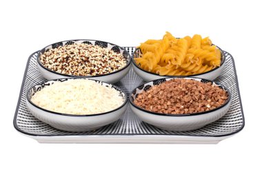 Sebze yemeği. Dört kâse karabuğday, erişte, pirinç ve beyaz arka planda izole edilmiş kinoa ile dekoratif bir tabak makro. Sağlıklı beslenme.