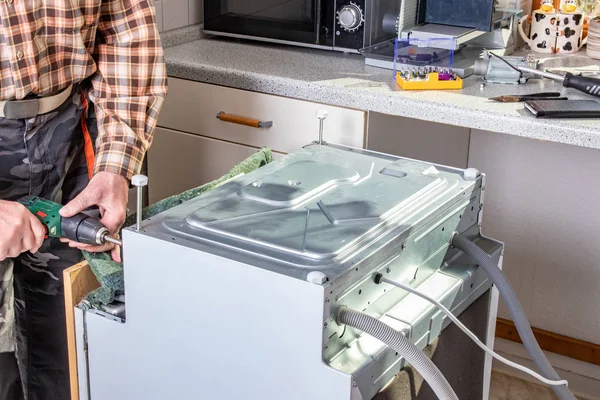 People in technician jobs. A broken built-in dishwasher in a whi