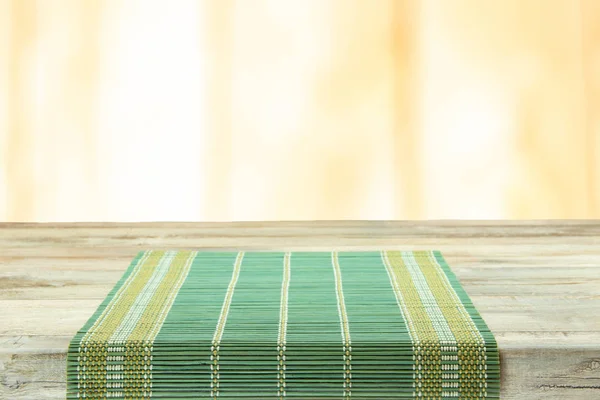 Empty table with green tablecloth over bright background. For yo