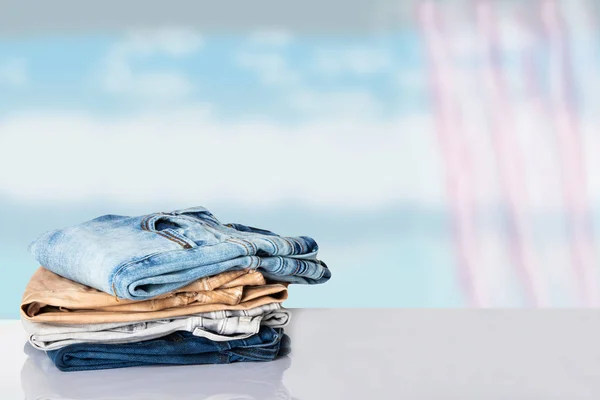 Pila de ropa colorida. Montón de pantalones vaqueros de colores en la mesa blanca wi —  Fotos de Stock