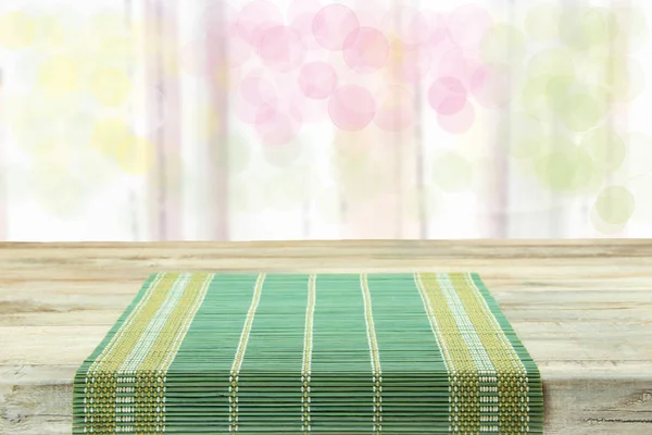 Empty table with green tablecloth over bright bokeh background.