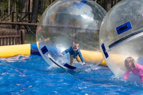 Water or aqua zorbing. Children play inside the inflatable trans