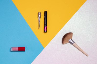 Renkli güzellik ürünleri, makyaj ürünleri ve fırça, kaş kalemi ve ruj gibi parlak pembe, sarı ve mavi arkaplan üzerinde kopya alanı olan araçların dekoratif bileşimi reklam, tasarım, kapak ve kozmetik arka plan..