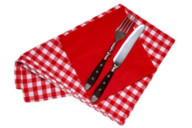 Servis çatal bıçak takımı izole. Kırmızı kareli peçetedeki eski bir çatal ve bıçağın beyaz arka planda izole edilmiş hali..