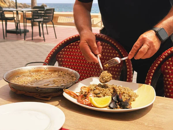 Costa Brava 'daki Akdeniz kıyısındaki bir İspanyol restoranında bir garson deniz mahsullü paella servis ediyor. Akdeniz 'de sağlıklı yiyecekler.
