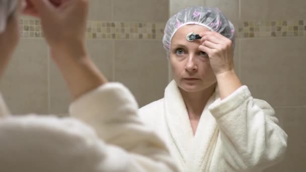 Donna con una maschera sul viso davanti allo specchio in bagno — Video Stock