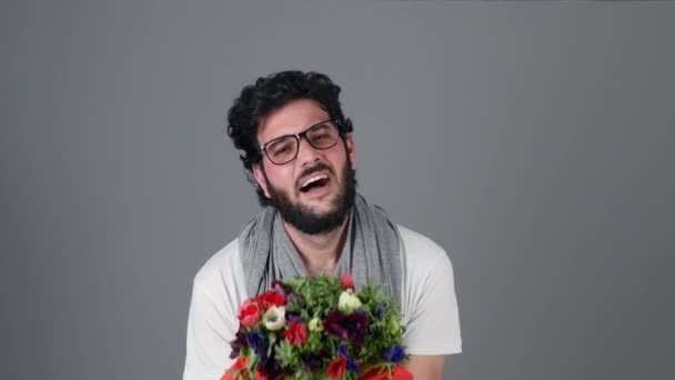 Beau jeune homme sur le mur gris tenant bouquet de fleurs et s'excuser — Video