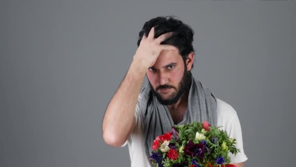 Beau jeune homme tenant bouquet de fleurs et touche sa barbe — Video